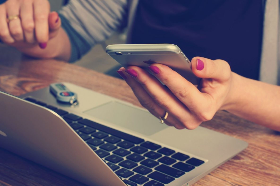 Une femme utilisant un smartphone et un ordinateur portable