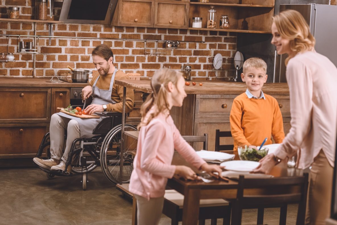 Un homme en fauteuil roulant cuisiner avec sa famille  