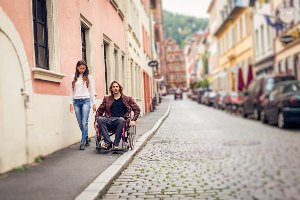 un homme conduisant un fauteuil roulant dans la rue