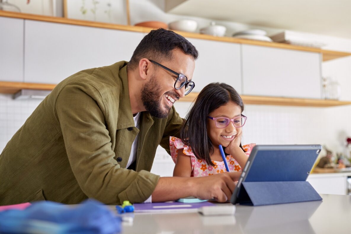 Un père souriant aide sa petite fille à faire ses devoirs