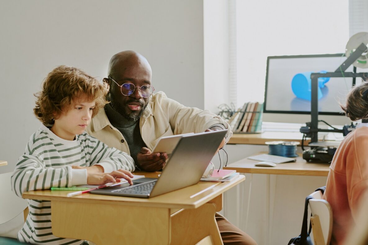 Un professeur et un élève utilisent l'ordinateur